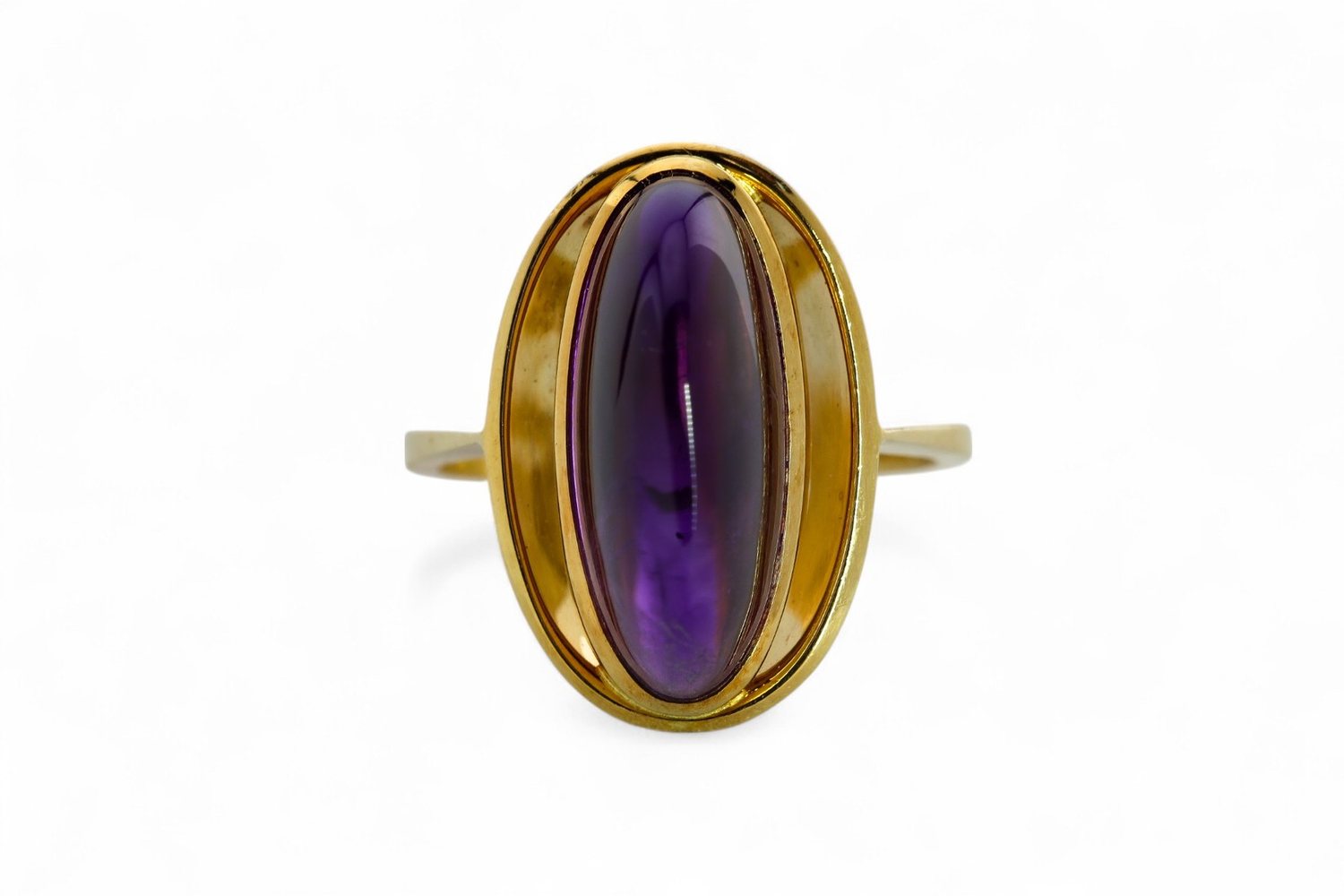 An amethyst cabochon ring in yellow gold, photographed on white