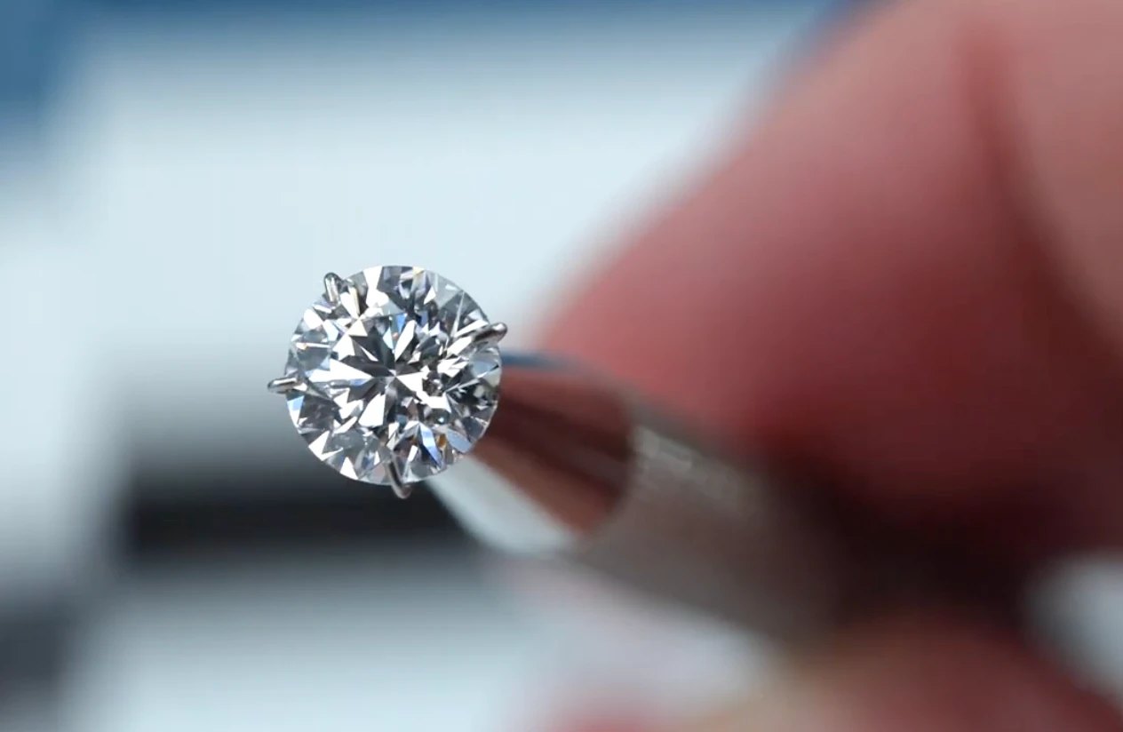 A round brilliant diamond held in tweezers