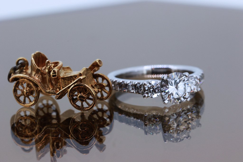 A gold carriage charm beside a diamond solitaire ring