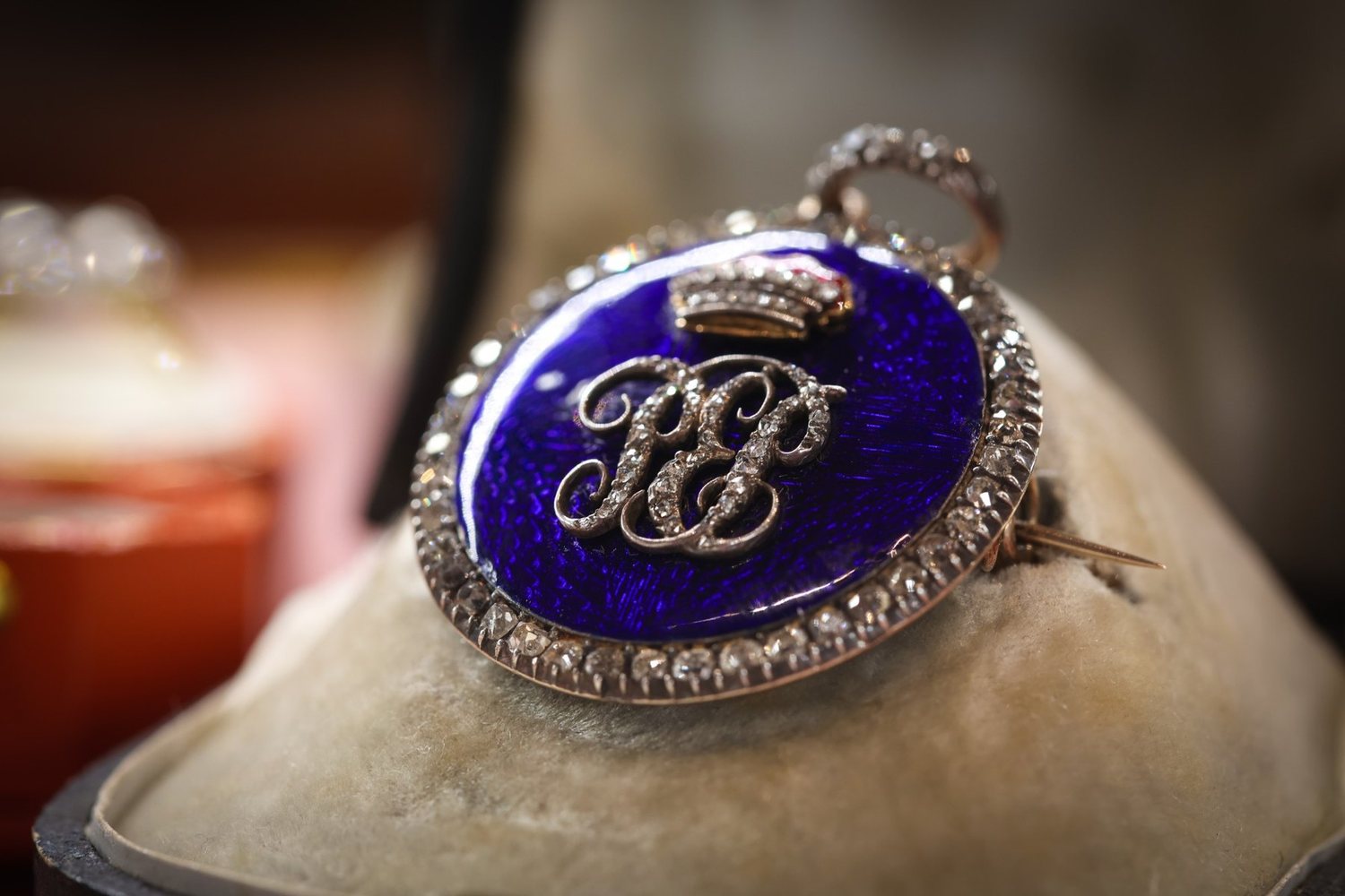 A blue enamel and rose diamond monogram brooch in its case