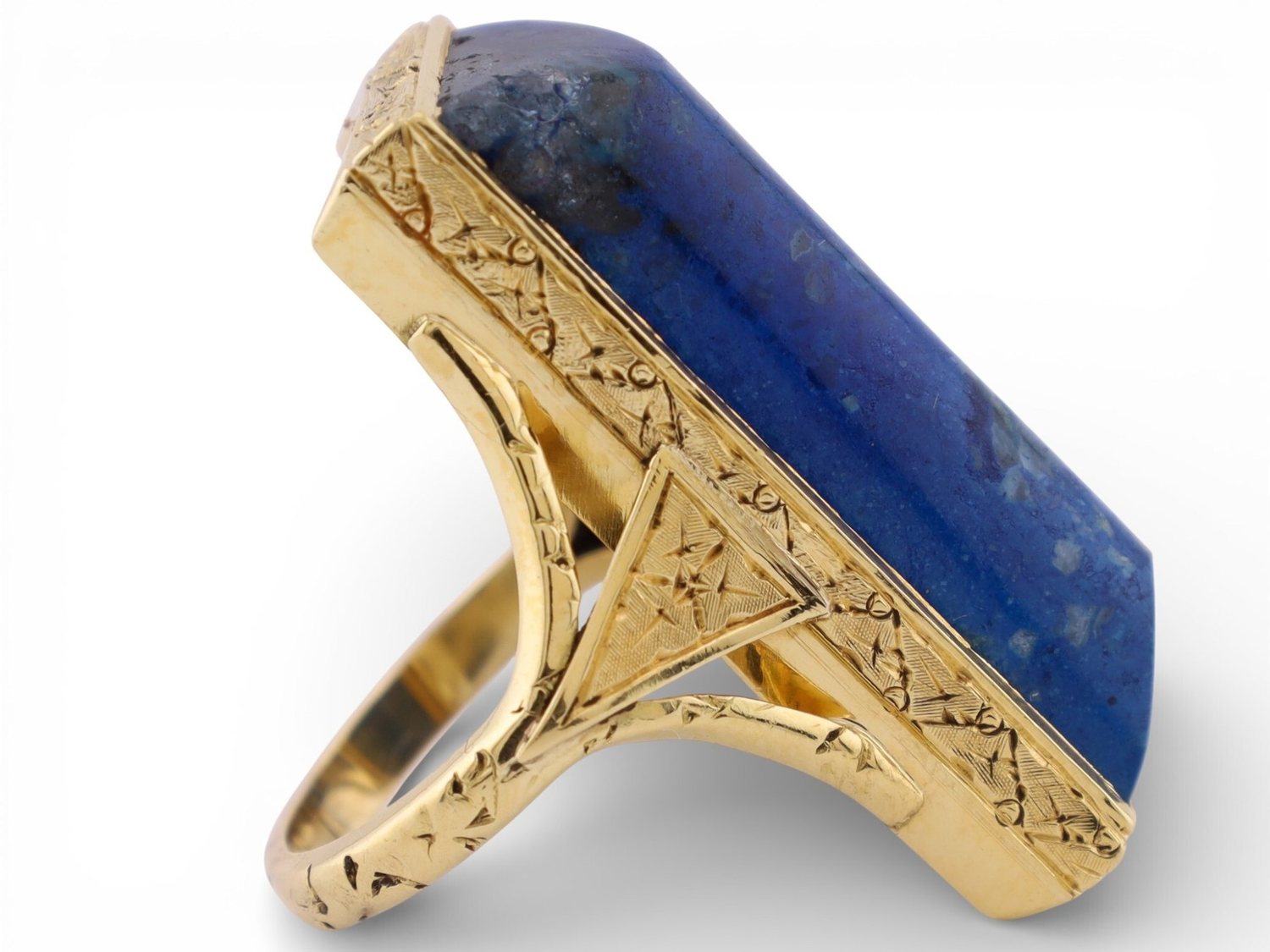 A lapis lazuli and engraved gold ring, photographed on white