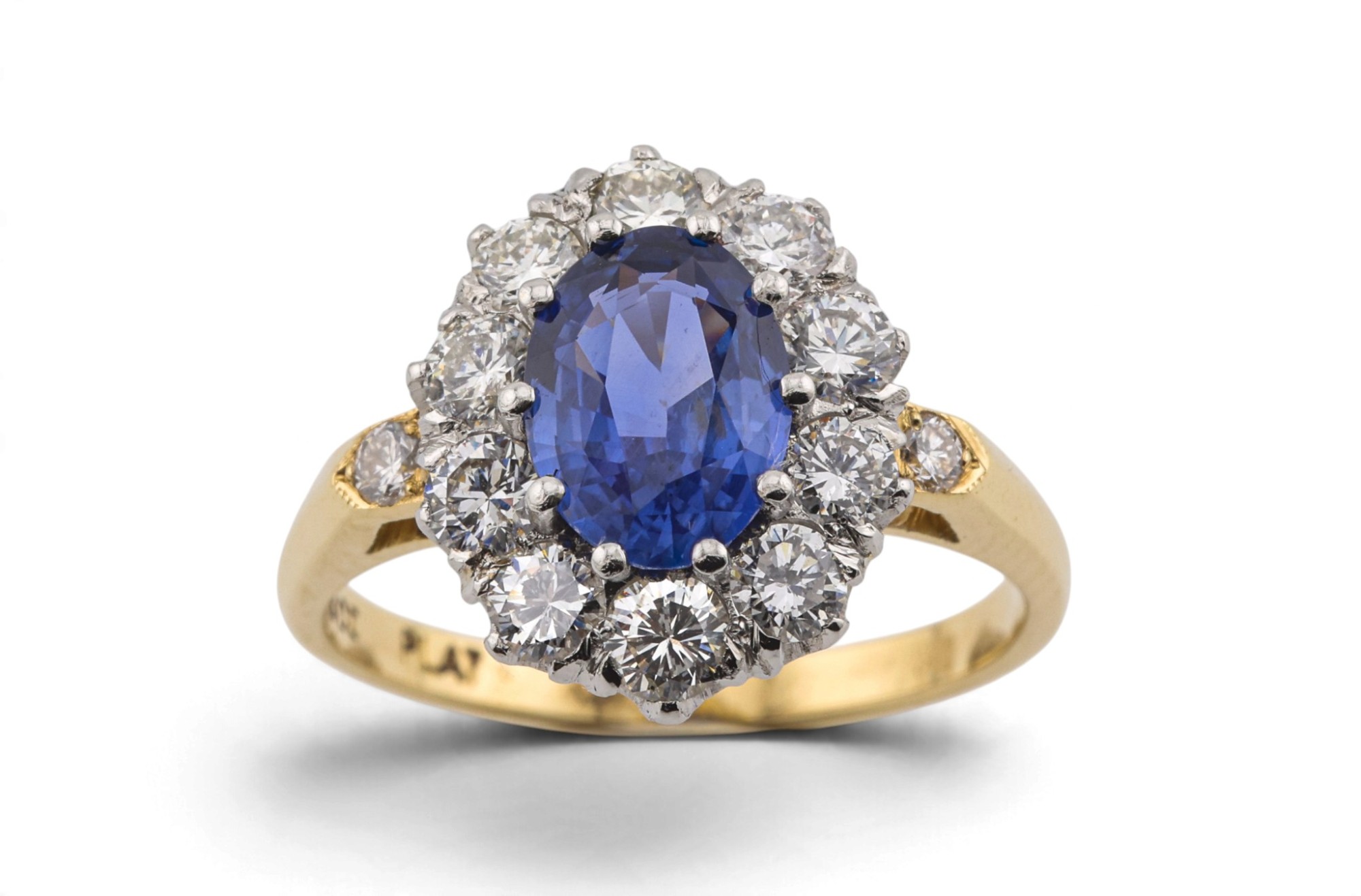 A sapphire and diamond cluster ring in yellow gold, photographed on white